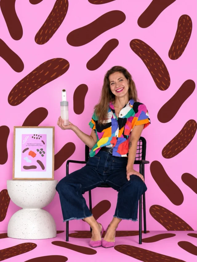 Naeratav naine toolil, käes Electric Moley bidee ja kõrval raamitud Moley plakat